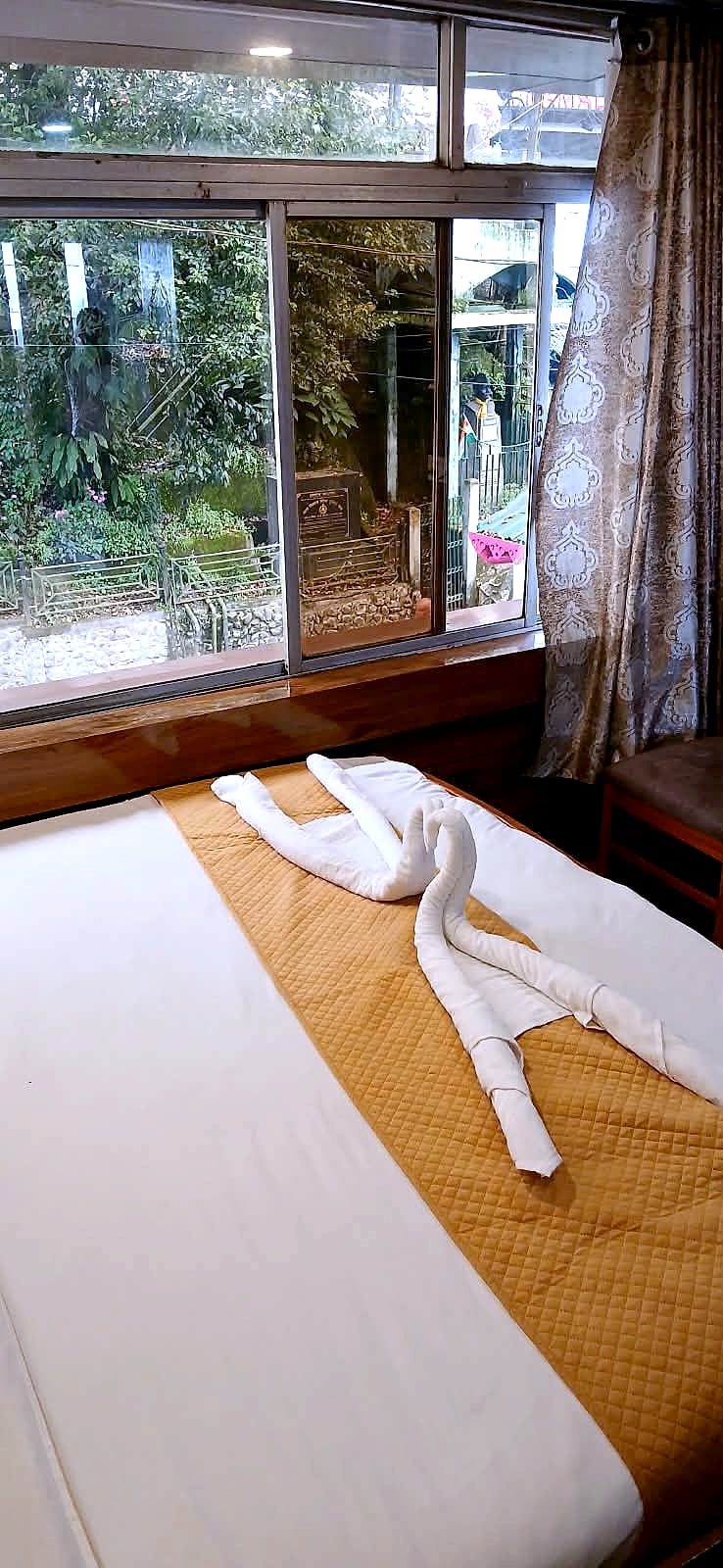 Room 203: the bed by the window, with a towel swan and the trees outside